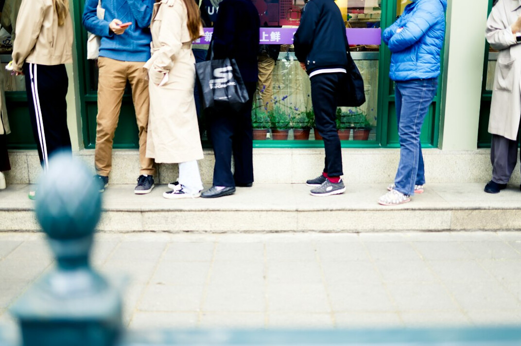 Close view of people waiting patiently in a line outside a shop