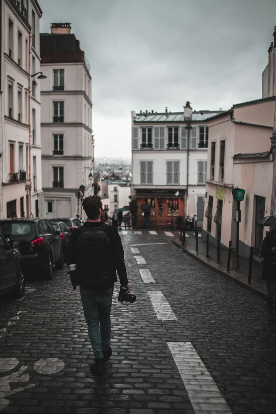 Photographer holding a camera while walking through a city street