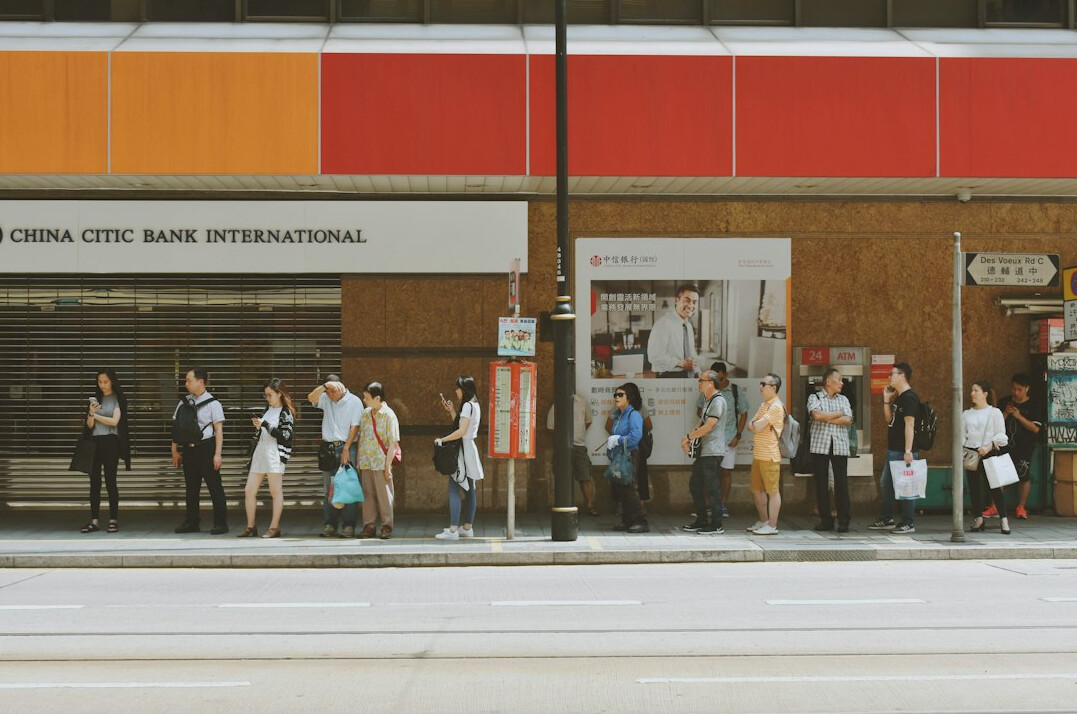 People standing in a line waiting at a bus stop